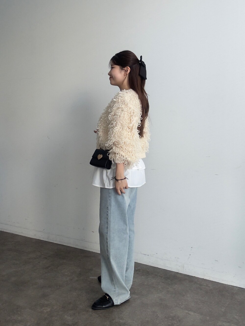 ホワイト系のスカート、ホワイト系のカーディガン/ボレロ、ブルー系のデニムパンツを着用したレディースの秋コーディネートの2枚目の写真