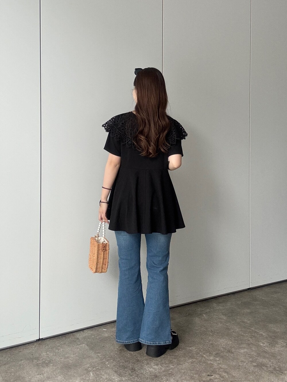 ブラック系のTシャツ/カットソー、ブルー系のデニムパンツ、ベージュ系のショルダーバッグを着用したレディースの春コーディネートの3枚目の写真