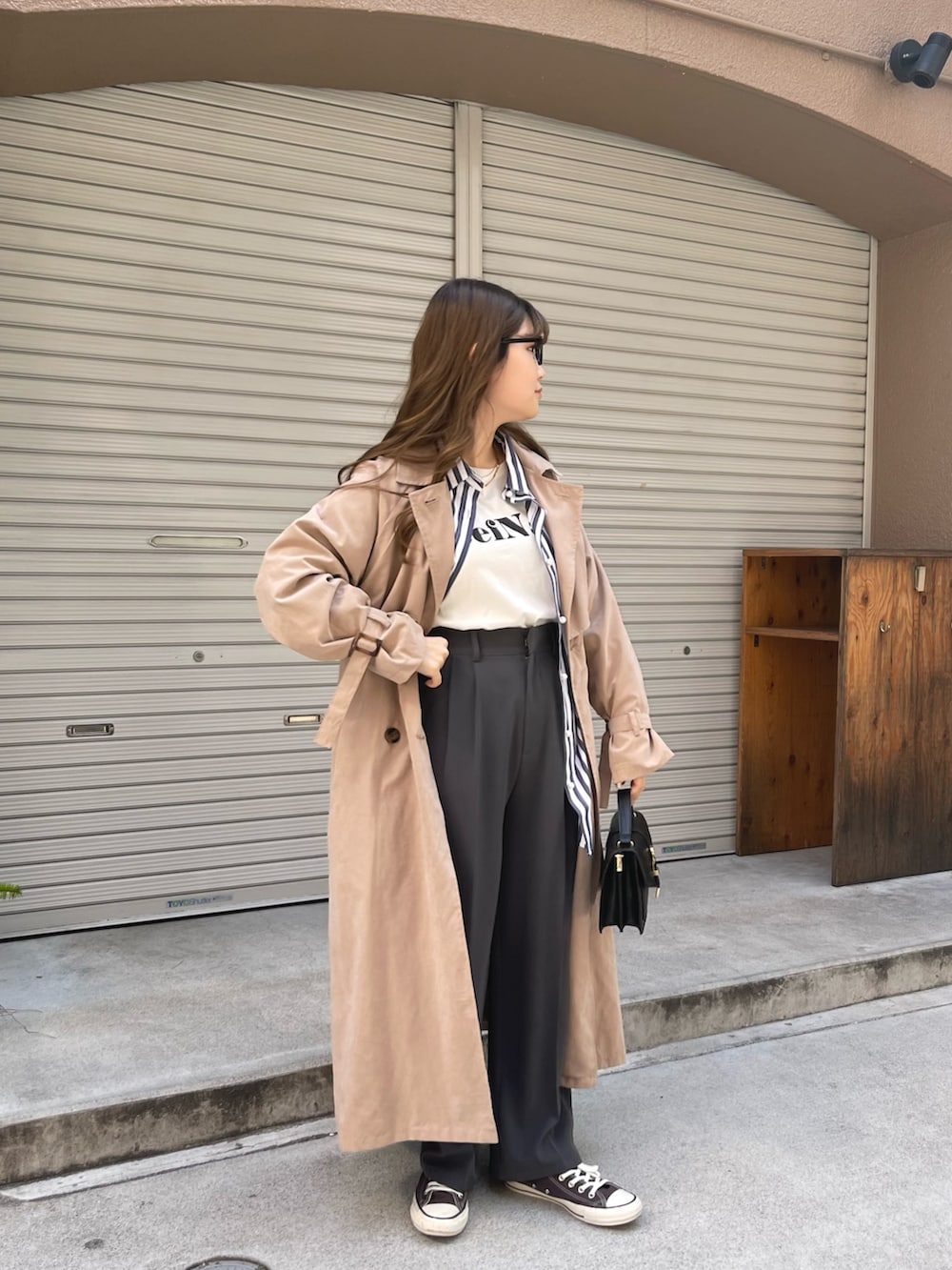 ベージュ系のトレンチコート、ブルー系のシャツ/ブラウス、ホワイト系のTシャツ/カットソーを着用したレディースの春コーディネートの3枚目の写真