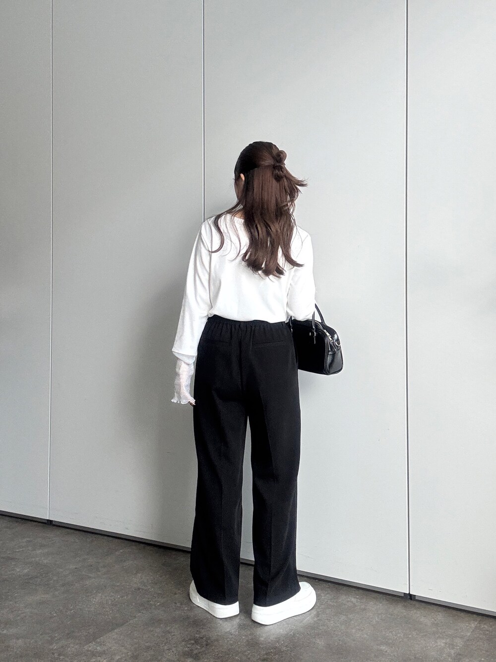 ホワイト系のTシャツ/カットソー、ブラック系のスラックス、ブラック系のボストンバッグを着用したレディースの春コーディネートの4枚目の写真