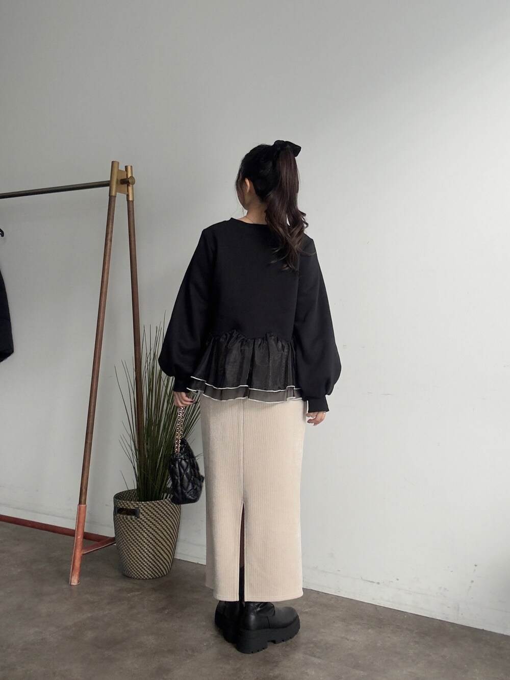 ブラック系のスウェット、ブラック系のブーツ、ベージュ系のスカートを着用したレディースの秋コーディネートの3枚目の写真