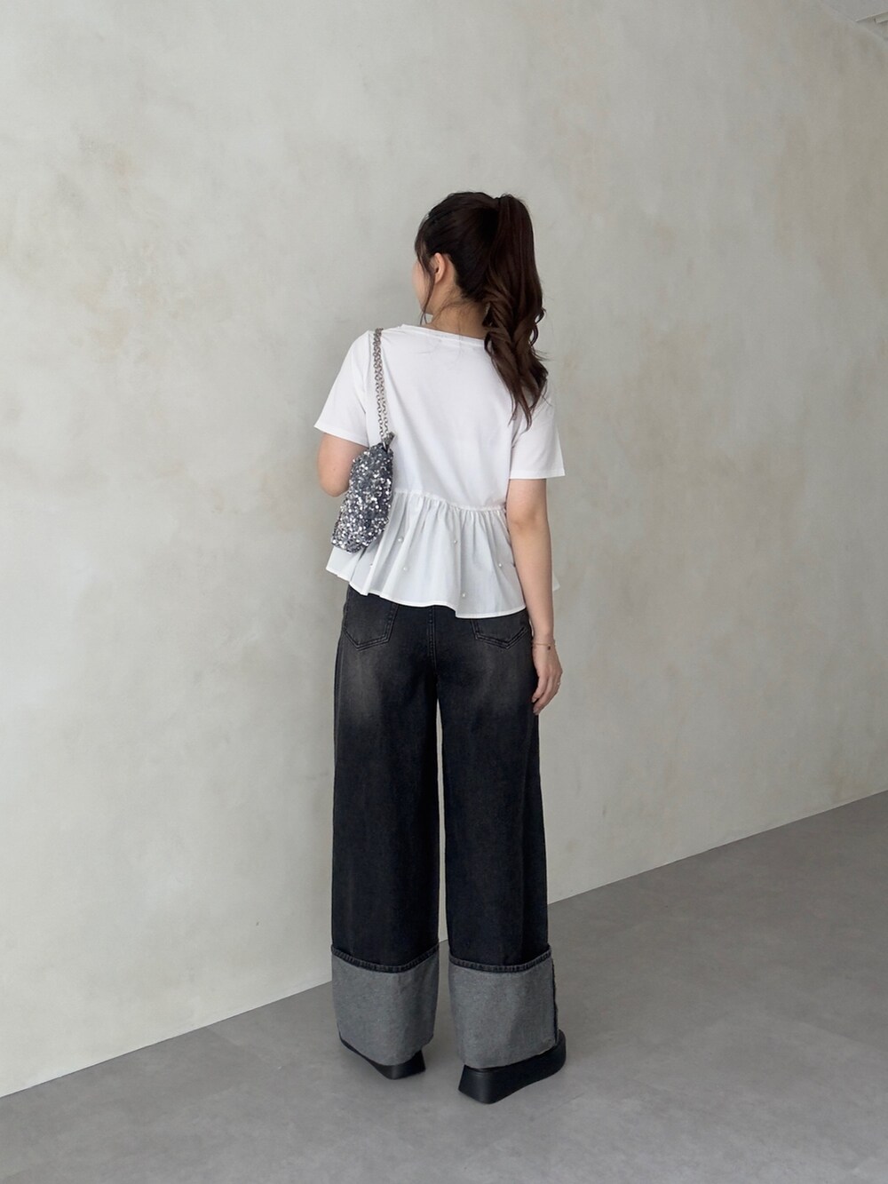 シルバー系のショルダーバッグ、ブラック系のデニムパンツ、ブラック系のサンダルを着用したレディースの夏コーディネートの3枚目の写真