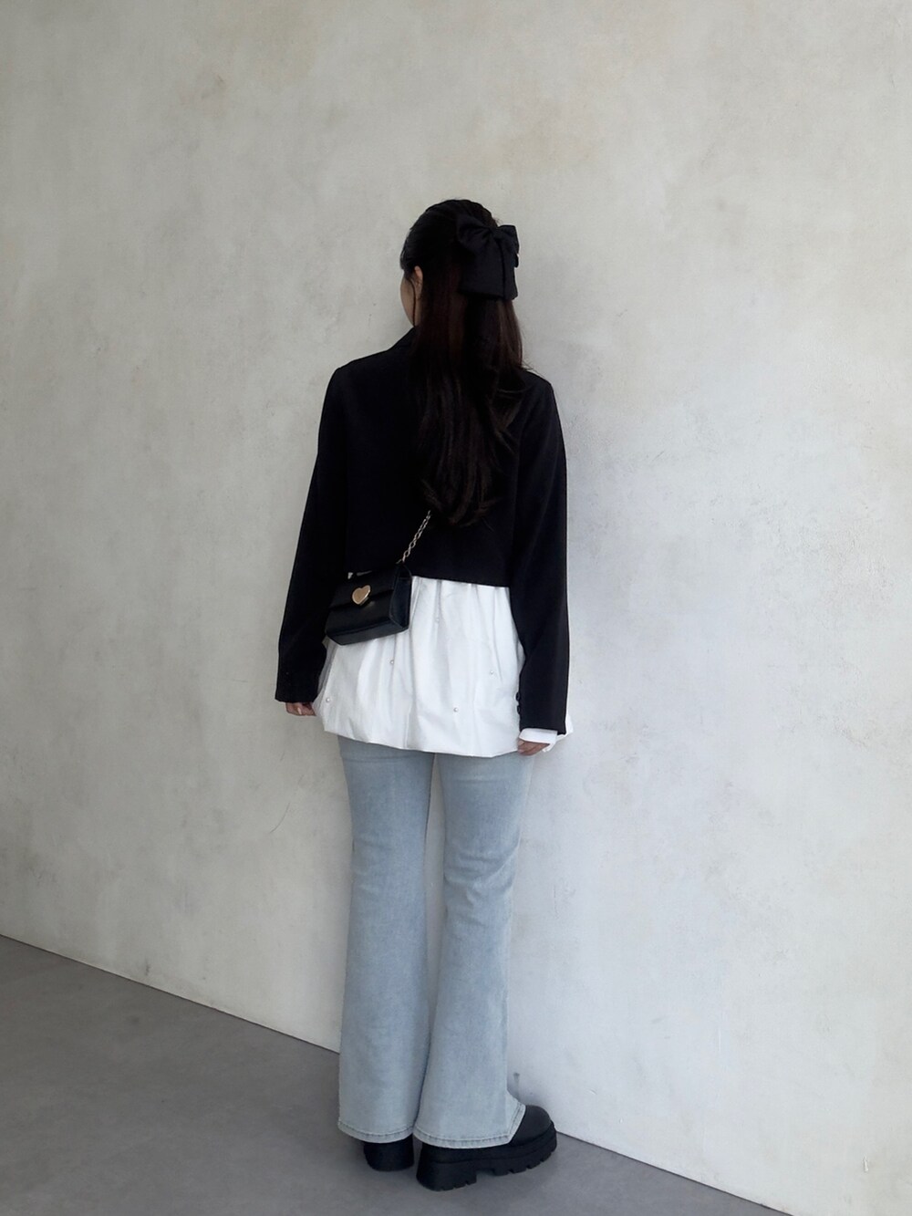 ブルー系のデニムパンツ、ブラック系のブーツ、ブラック系のテーラードジャケットを着用したレディースの秋コーディネートの3枚目の写真