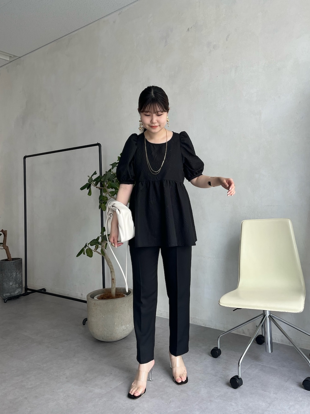 ブラック系のパンプス、ブラック系のパンツドレス、ゴールド系のネックレスを着用したレディースの春コーディネートの3枚目の写真