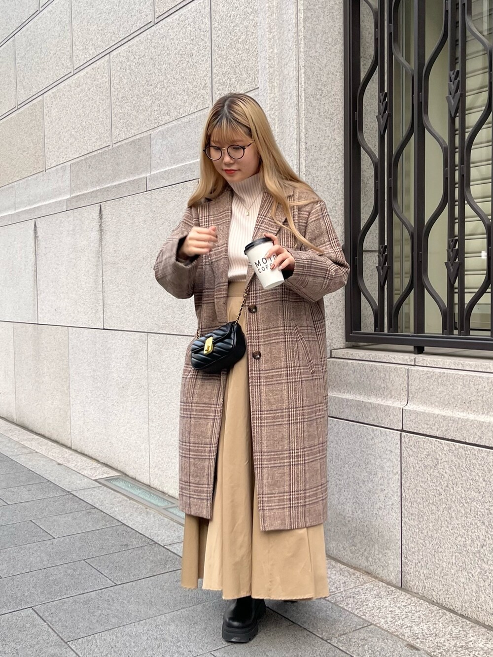 ホワイト系のニット/セーター、ブラウン系のチェスターコート、ベージュ系のスカートを着用したレディースの秋コーディネートの2枚目の写真