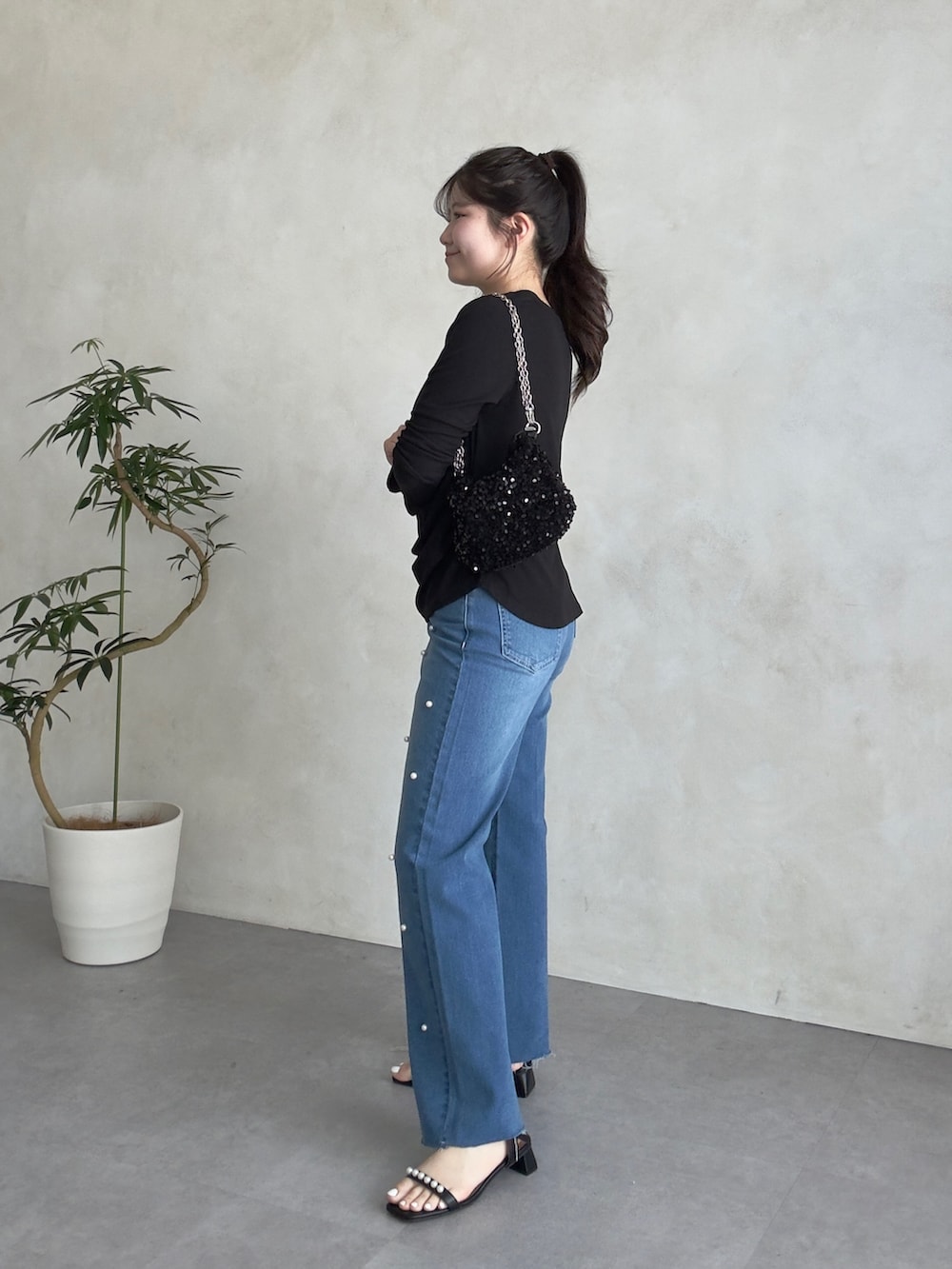 ブラック系のサンダル、ブルー系のデニムパンツ、ブラック系のTシャツ/カットソーを着用したレディースの春コーディネートの2枚目の写真