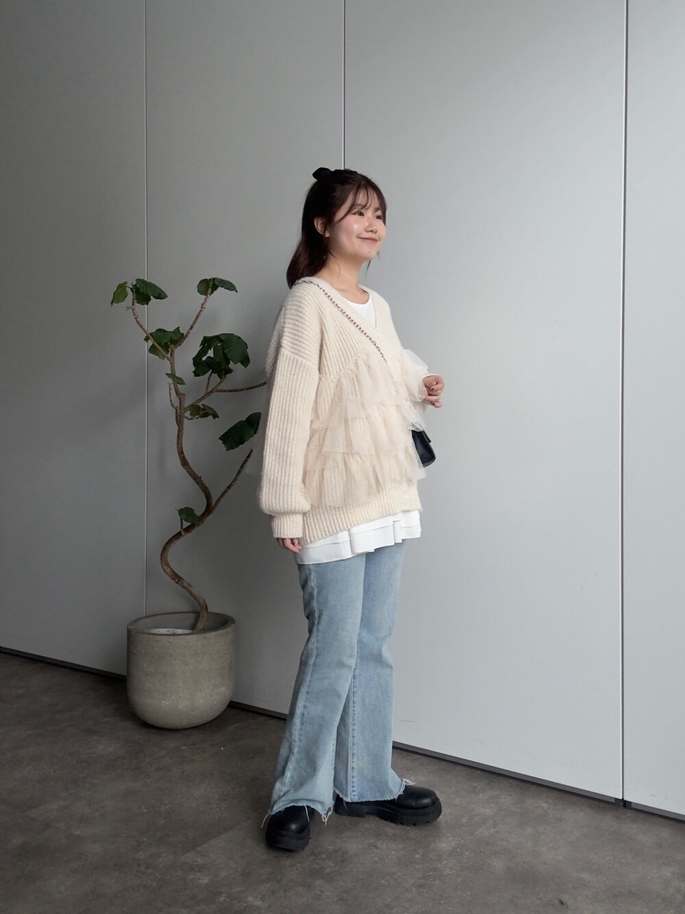 ベージュ系のカーディガン/ボレロ、ブラック系のブーツ、ブルー系のデニムパンツを着用したレディースの冬コーディネートの2枚目の写真