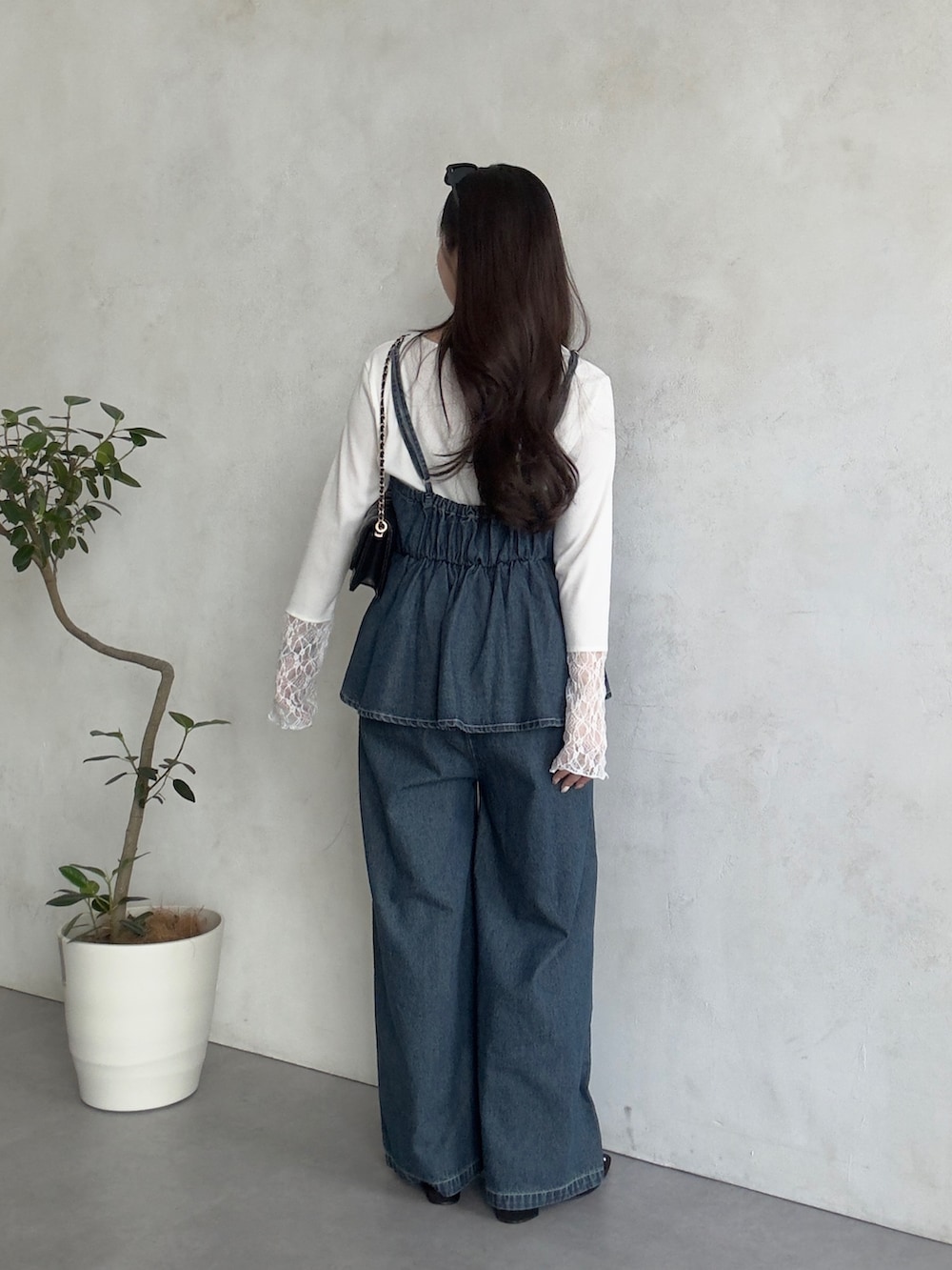 ブラック系のトートバッグ、ブルー系のサロペット/オーバーオール、ホワイト系のTシャツ/カットソーを着用したレディースの春コーディネートの3枚目の写真