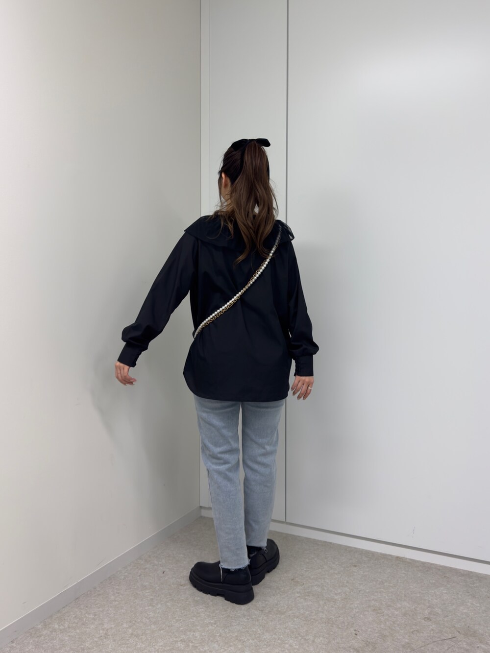 ブラック系のショルダーバッグ、ブルー系のデニムパンツ、ブラック系のシャツ/ブラウスを着用したレディースの冬コーディネートの2枚目の写真