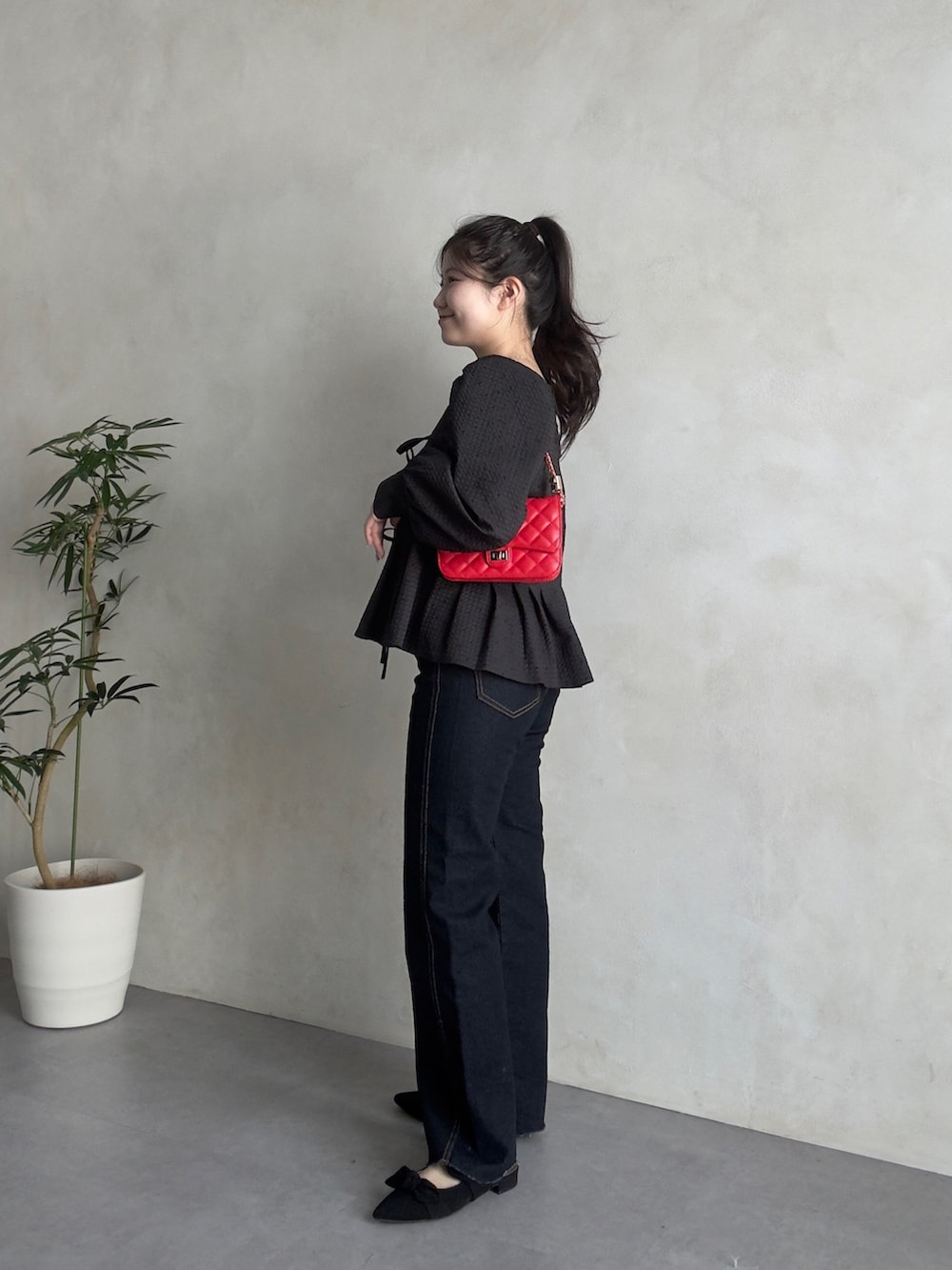 ブルー系のデニムパンツ、ブラック系のパンプス、レッド系のトートバッグを着用したレディースの春コーディネートの2枚目の写真