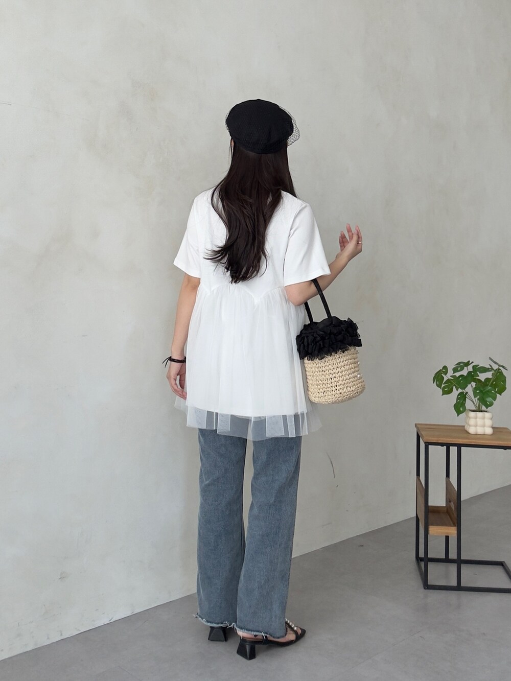 ベージュ系のかごバッグ、ブルー系のデニムパンツ、ブラック系のサンダルを着用したレディースの夏コーディネートの3枚目の写真