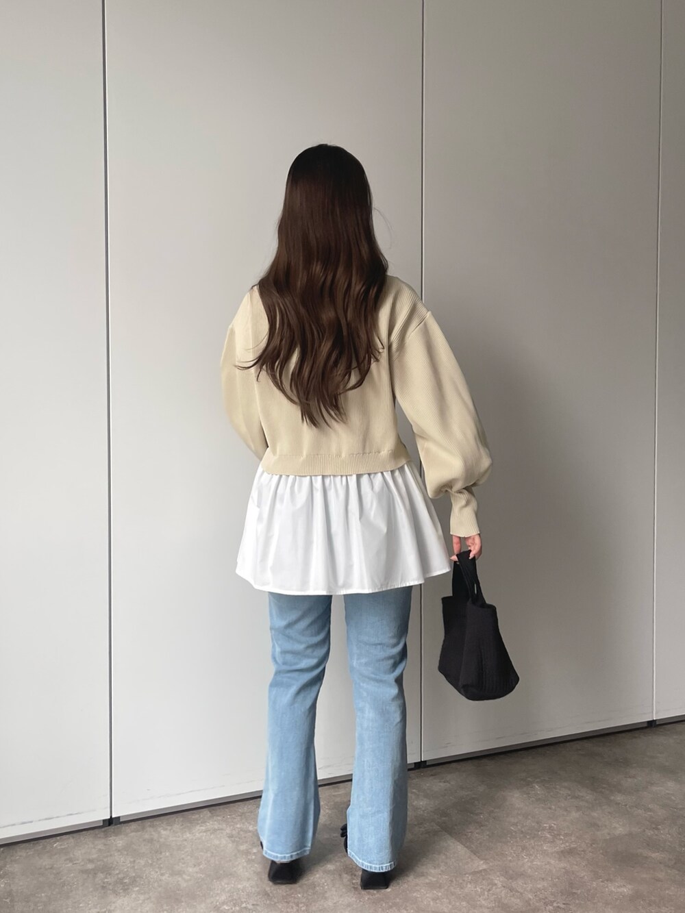 ホワイト系のカーディガン/ボレロ、ブルー系のデニムパンツ、ブラック系のトートバッグを着用したレディースの春コーディネートの2枚目の写真