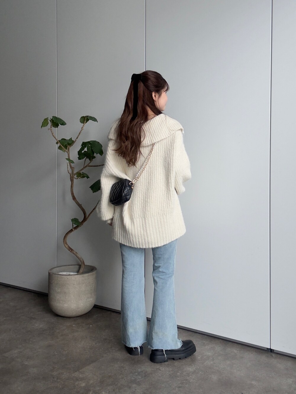 ホワイト系のニット/セーター、ホワイト系のTシャツ/カットソー、ブラック系のショルダーバッグを着用したレディースの冬コーディネートの3枚目の写真