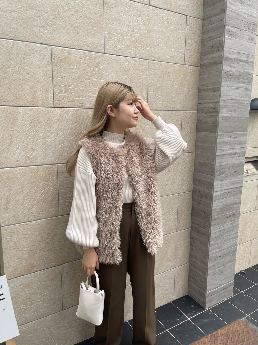 ホワイト系のニット/セーター、ベージュ系のベスト、ブラウン系のその他パンツを着用したレディースの秋コーディネートの2枚目の写真