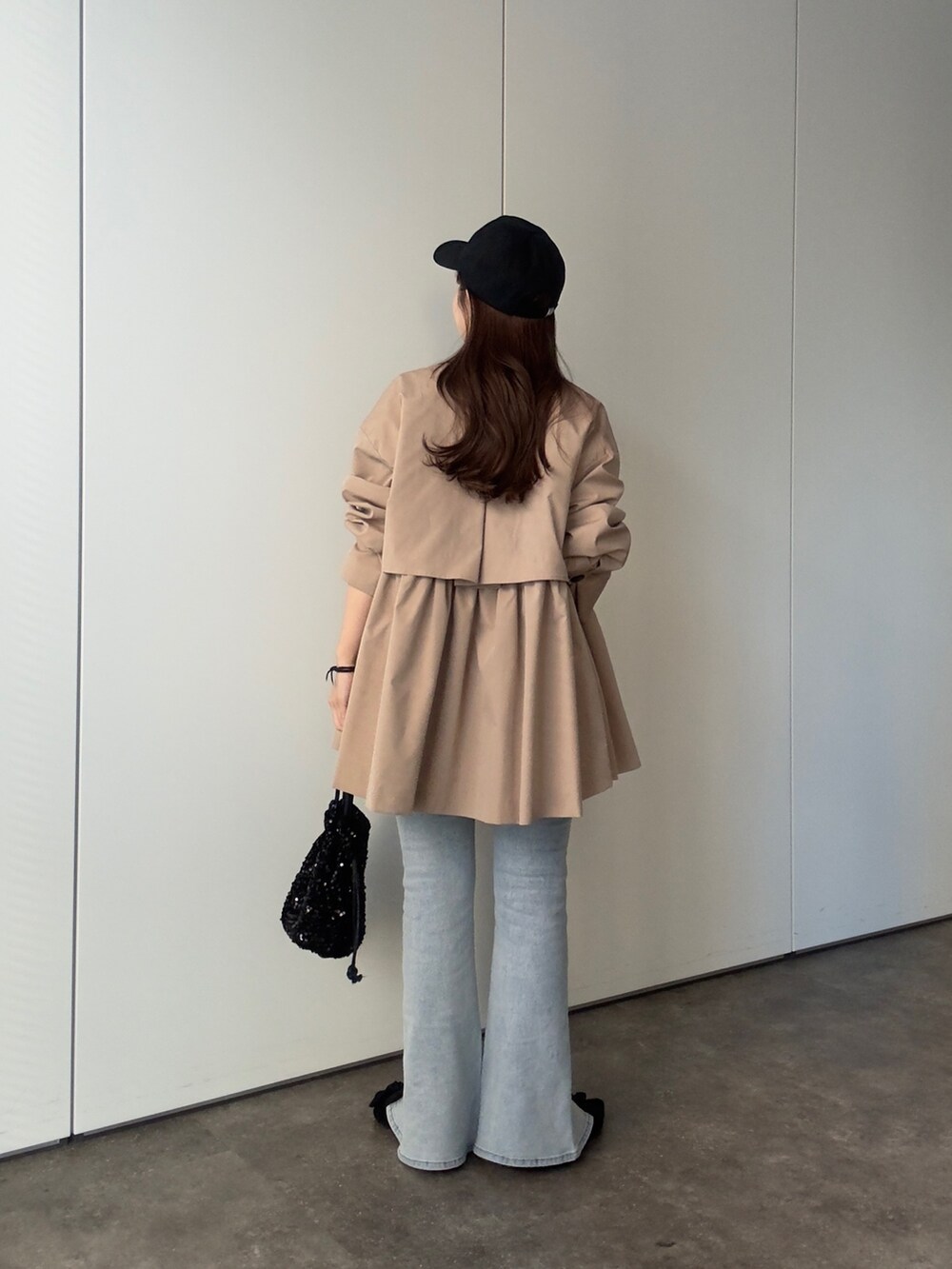 ベージュ系のトレンチコート、ブラック系のTシャツ/カットソー、ブルー系のデニムパンツを着用したレディースの春コーディネートの4枚目の写真