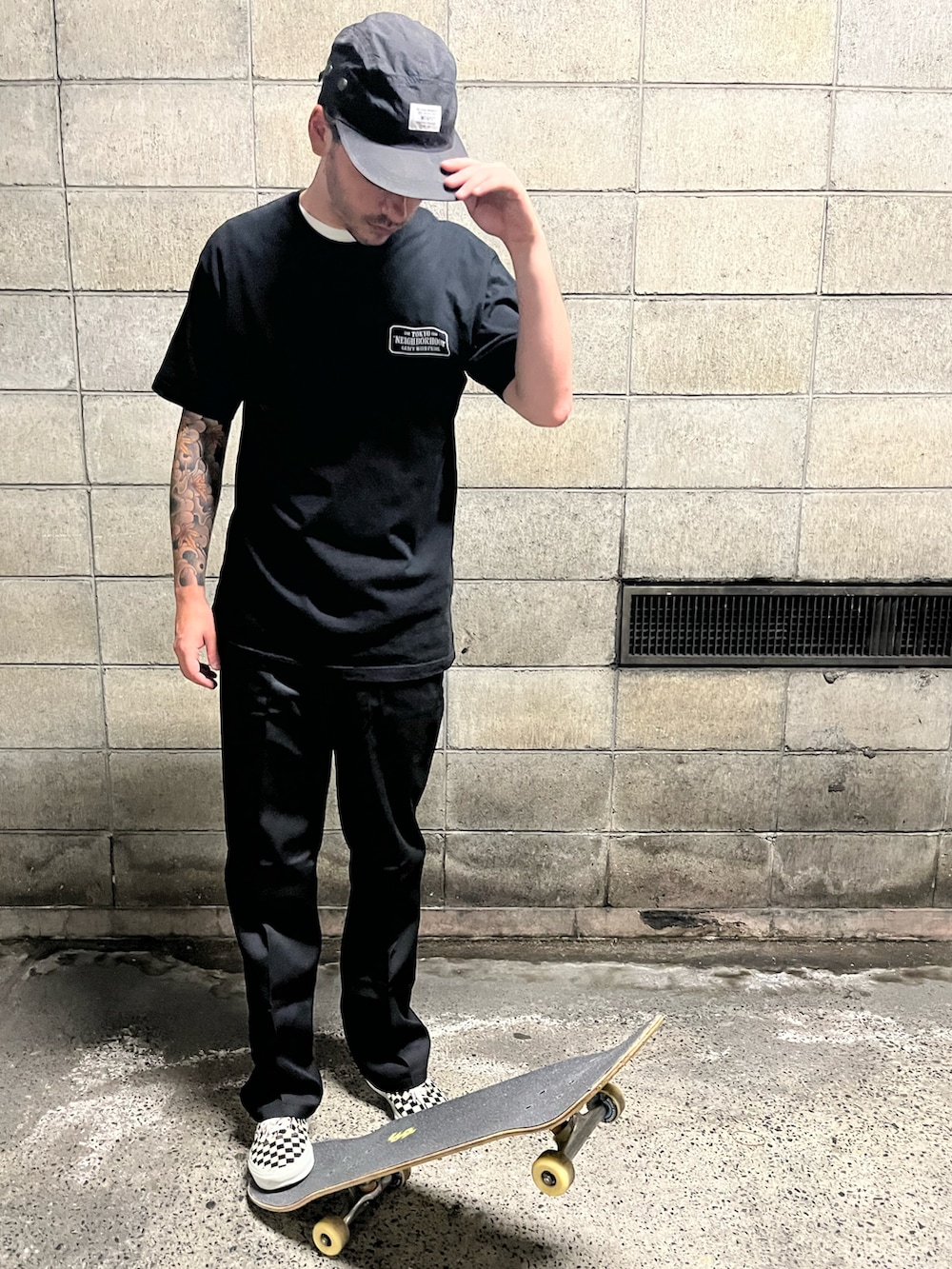 ブラック系のTシャツ/カットソー、ブラック系のチノパンツ、ホワイト系のスニーカーを着用したメンズの夏コーディネートの3枚目の写真