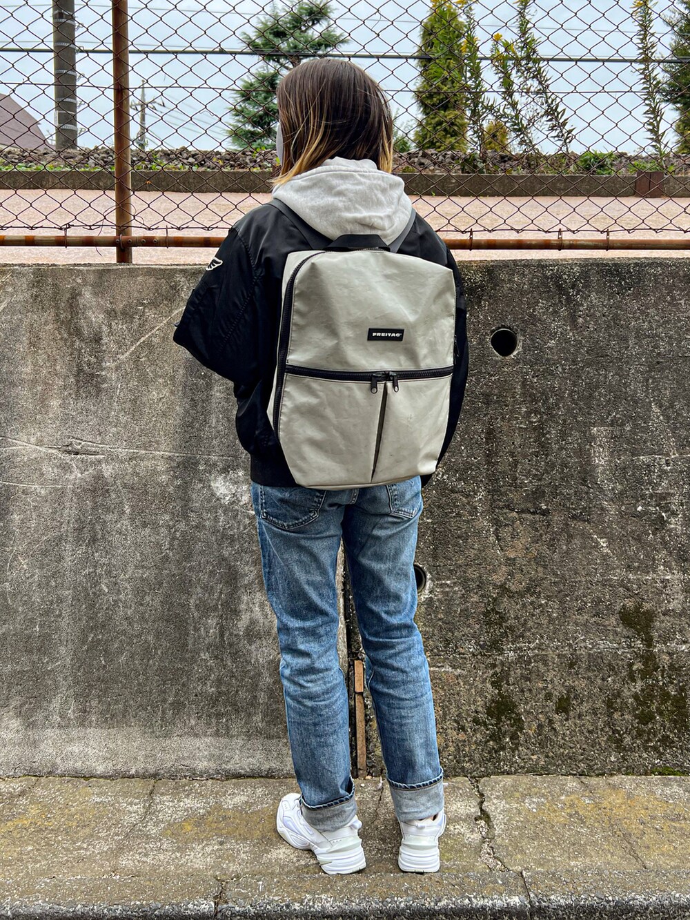 ブラック系のMA-1、ブルー系のデニムパンツ、ホワイト系のスニーカーを着用したレディースの秋コーディネートの4枚目の写真