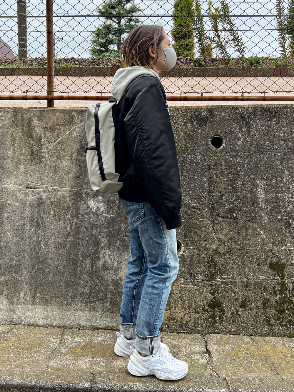 ブラック系のMA-1、ブルー系のデニムパンツ、ホワイト系のスニーカーを着用したレディースの秋コーディネートの3枚目の写真
