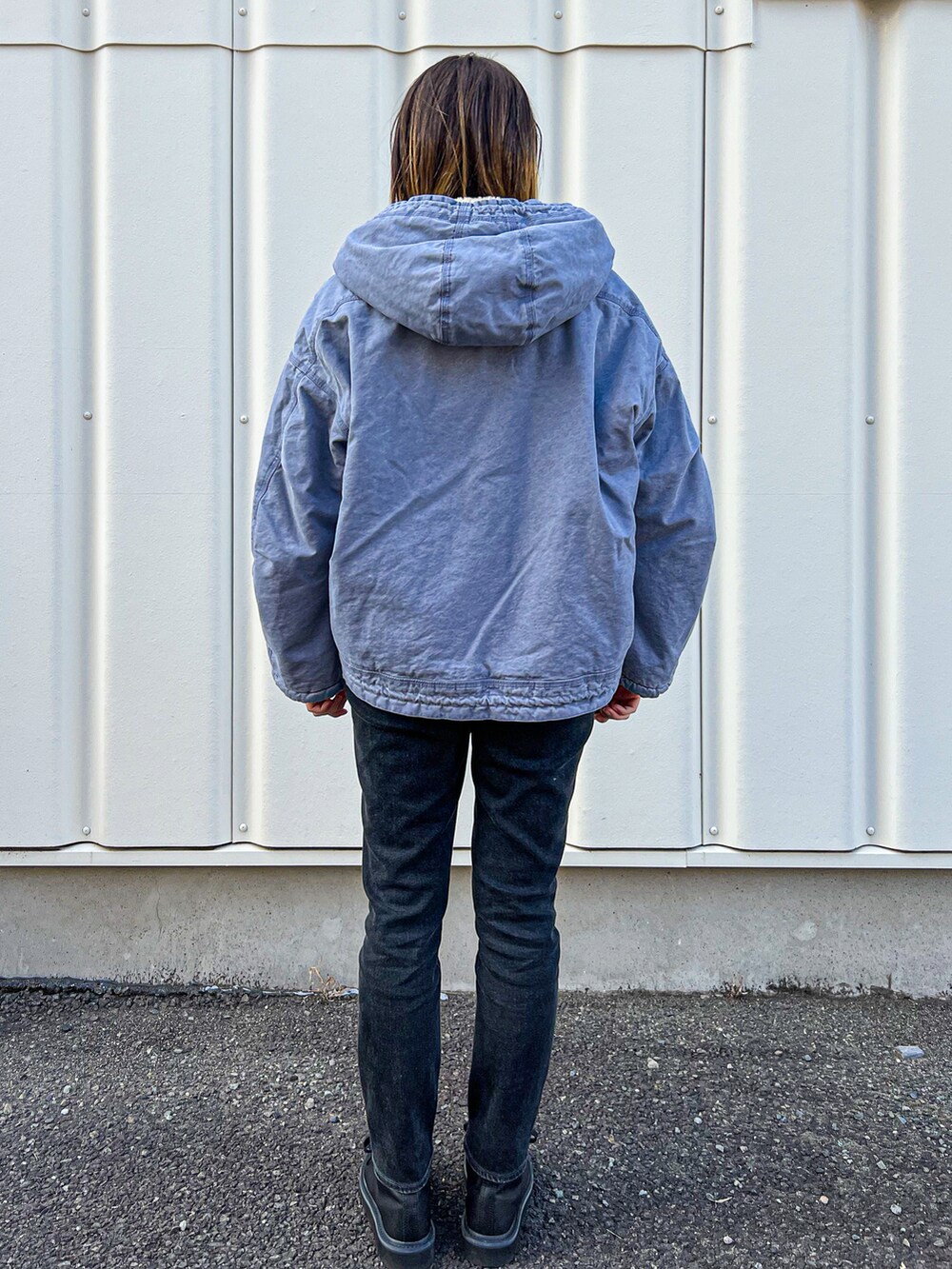 ブルー系のブルゾン、ブラック系のデニムパンツ、ブラック系のブーツを着用したレディースの秋コーディネートの3枚目の写真