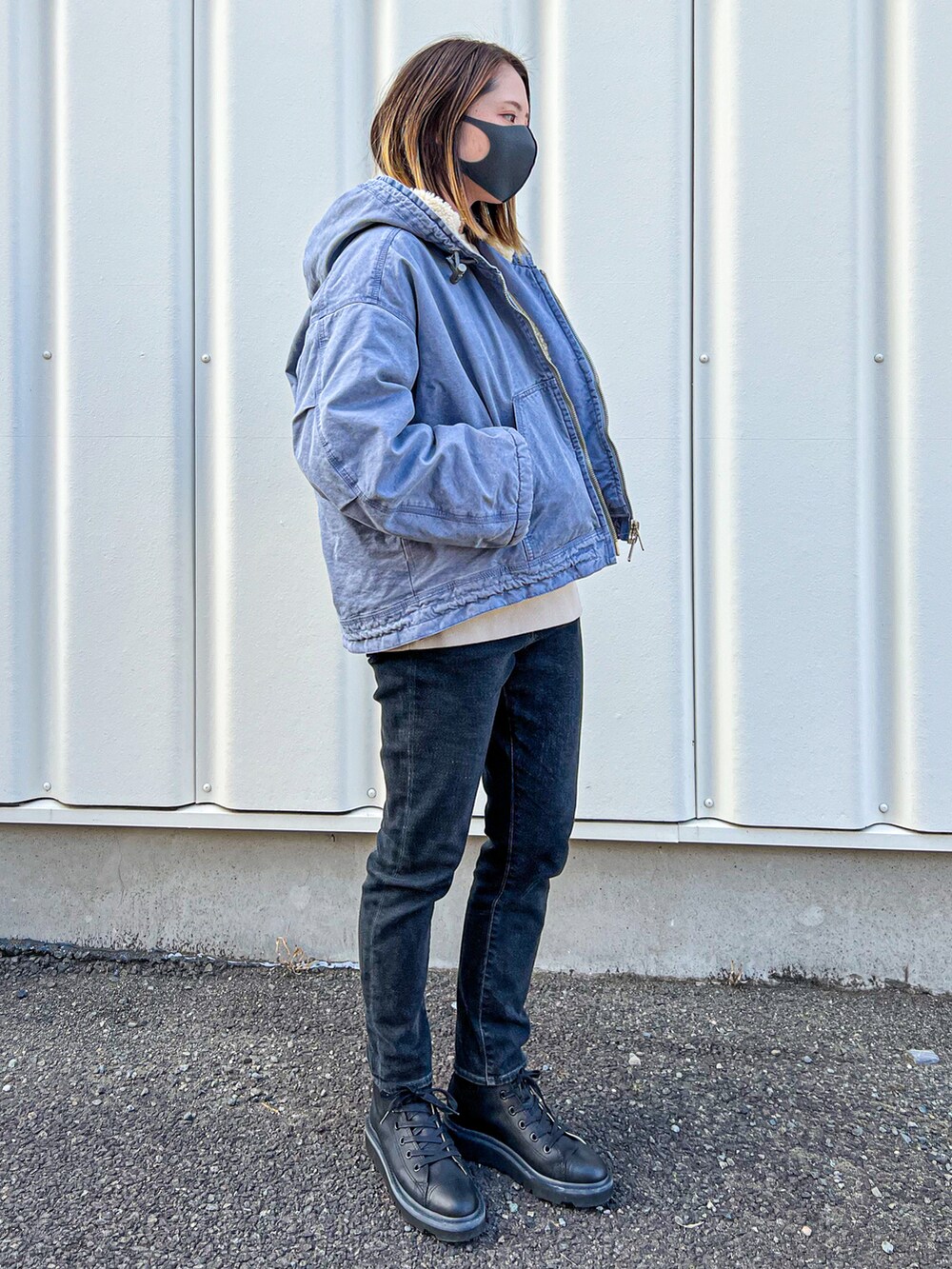 ブルー系のブルゾン、ブラック系のデニムパンツ、ブラック系のブーツを着用したレディースの秋コーディネートの2枚目の写真