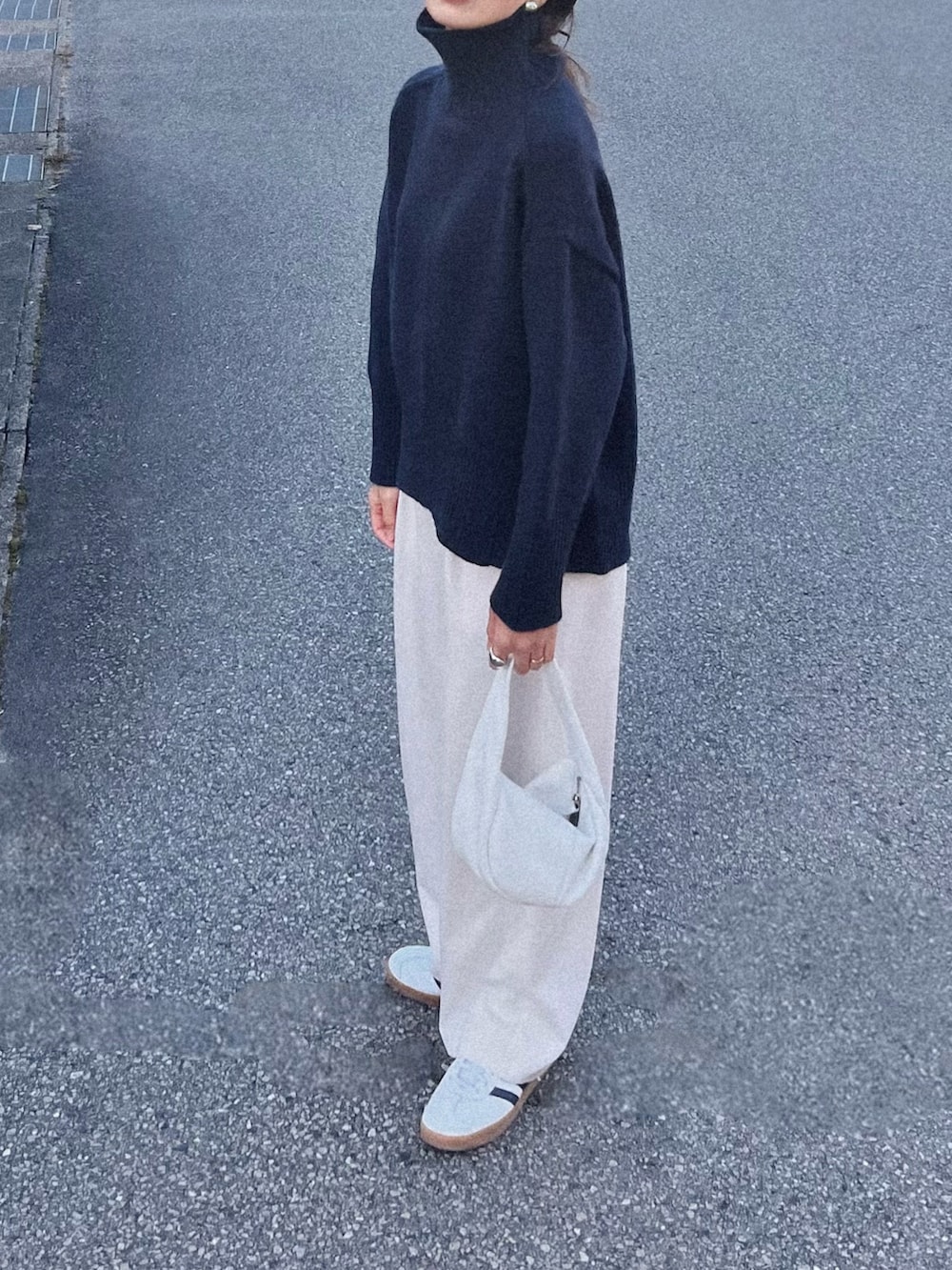 ブルー系のニット/セーター、ホワイト系のハンドバッグ、ホワイト系のスラックスを着用したレディースの秋コーディネートの2枚目の写真