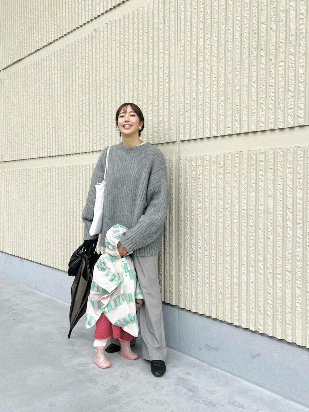 グレー系のカーディガン/ボレロ、ブラック系のハンドバッグ、ブラック系のレインシューズを着用したレディースの秋コーディネートの2枚目の写真