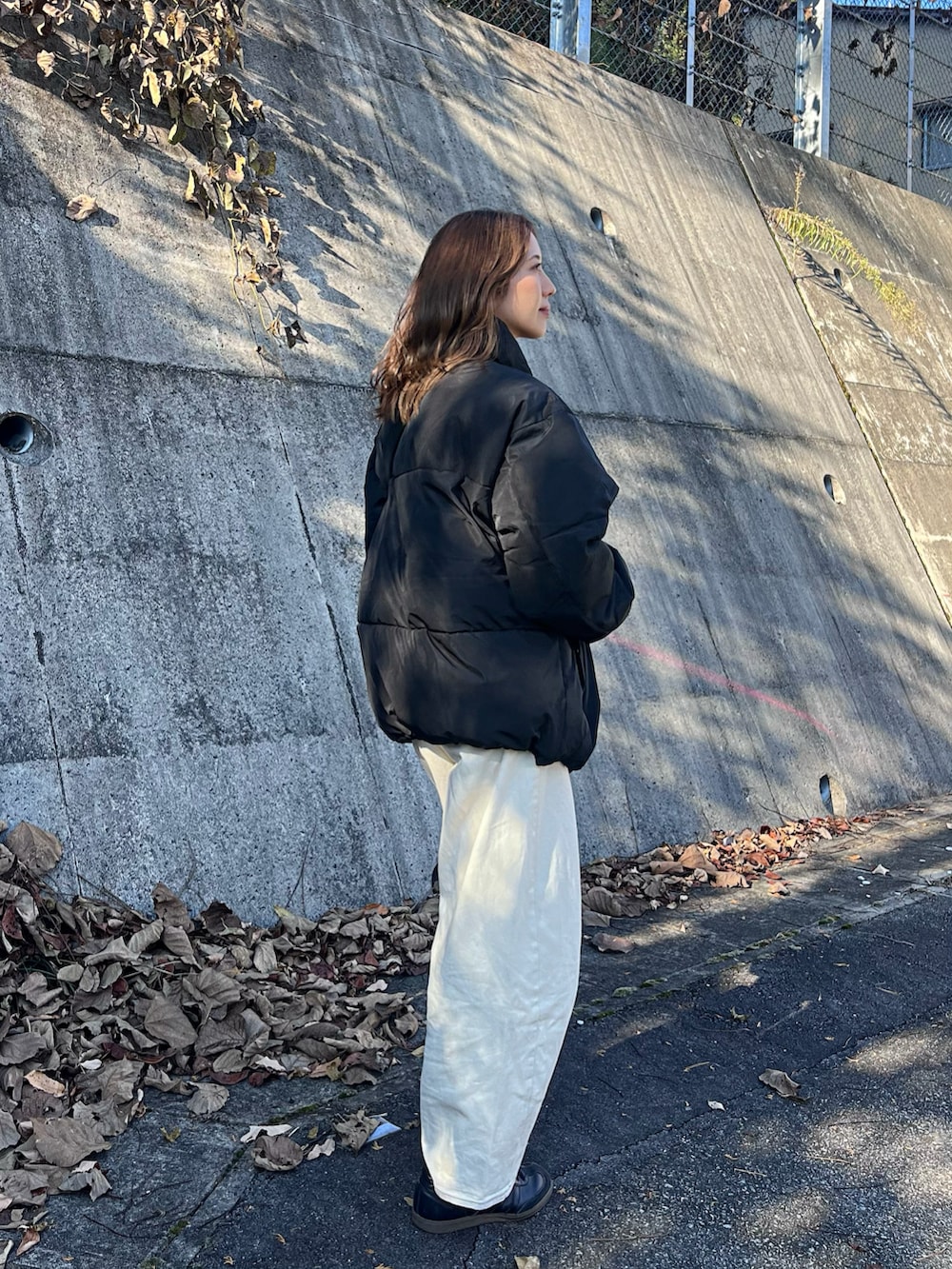 ブラック系のダウンジャケット/コート、ホワイト系のデニムパンツ、ブラック系のスニーカーを着用したレディースの秋コーディネートの3枚目の写真