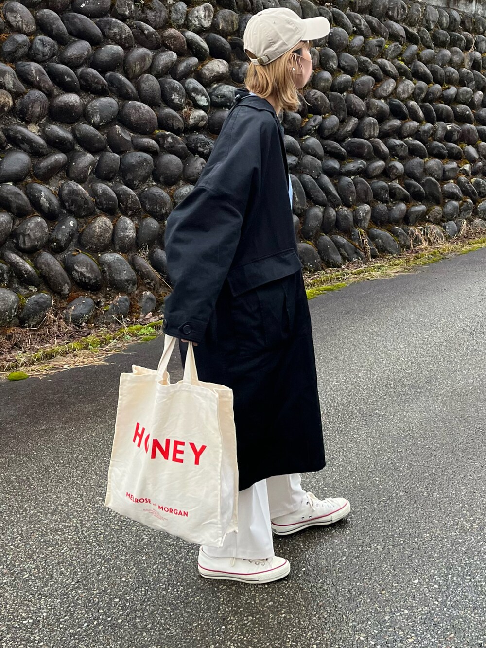 ブラック系のステンカラーコート、ホワイト系のスラックス、ホワイト系のスニーカーを着用したレディースの春コーディネートの2枚目の写真