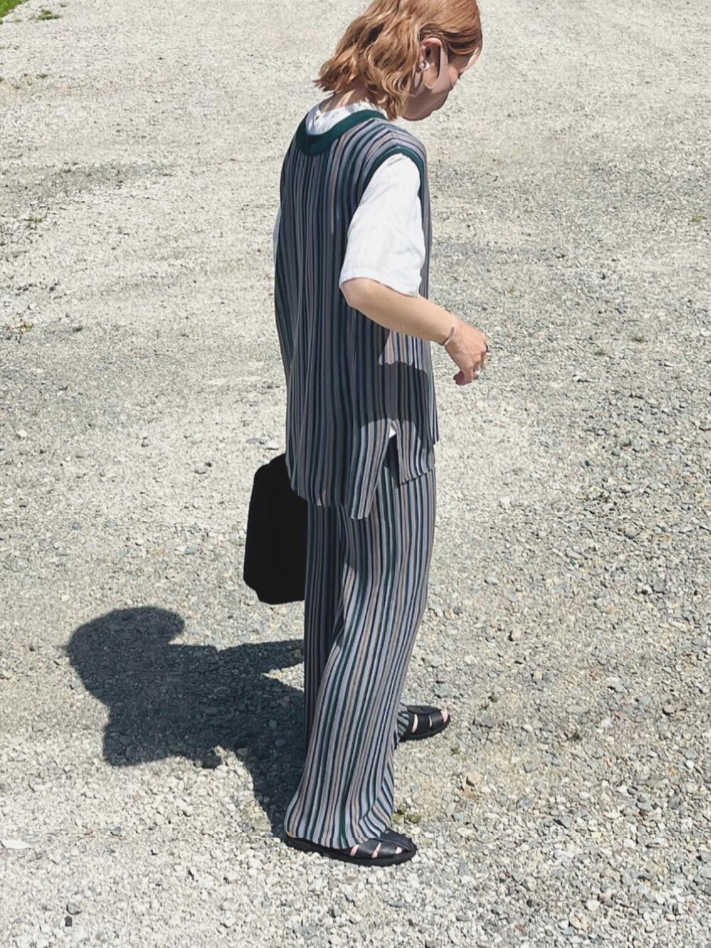 グレー系のセットアップ、ブラック系のサンダル、ブラック系のトートバッグを着用したレディースの春コーディネートの2枚目の写真