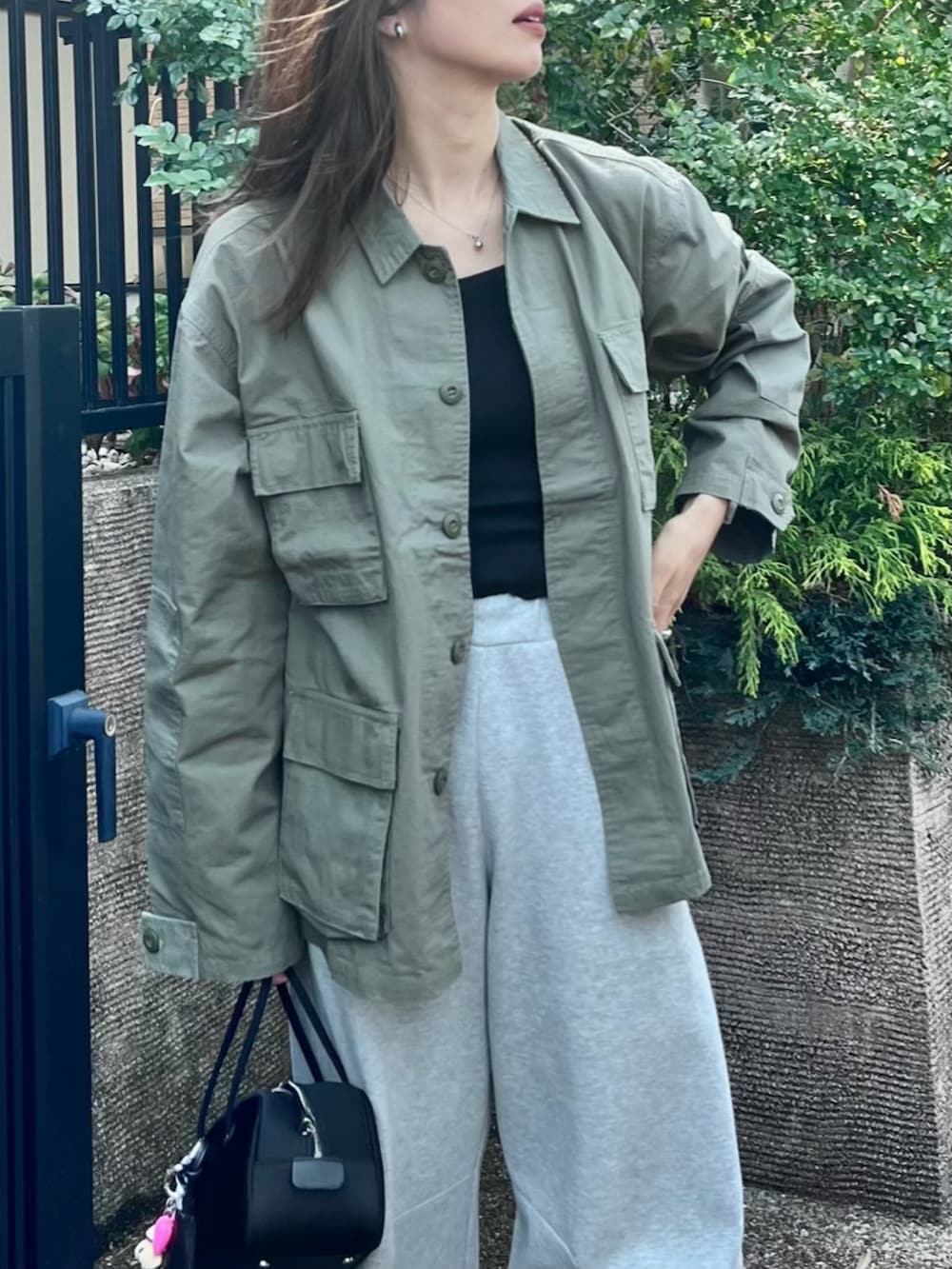 ブラック系のボストンバッグ、ブラック系のキャミソール、グリーン系のミリタリージャケットを着用したレディースの春コーディネートの2枚目の写真