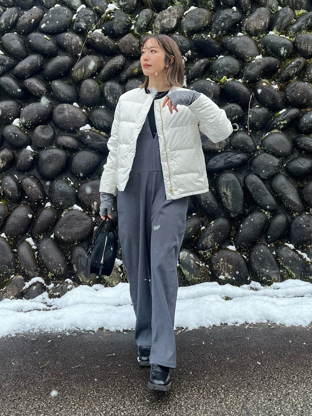 ホワイト系のダウンジャケット/コート、ブラック系のTシャツ/カットソー、ブラック系のボストンバッグを着用したレディースの冬コーディネートの2枚目の写真