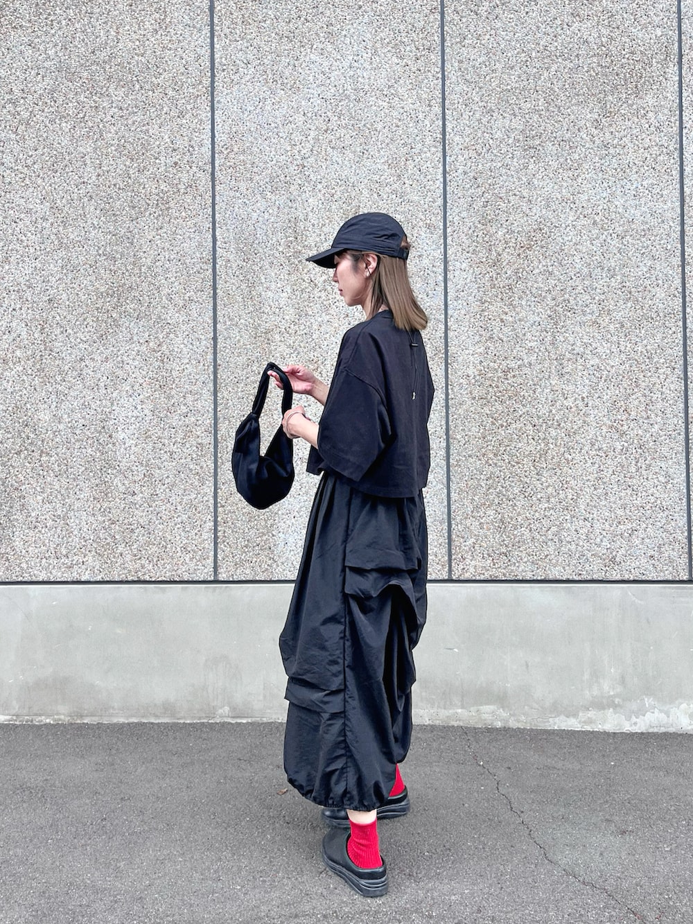 ブラック系のTシャツ/カットソー、ブラック系のスカート、ブラック系のスニーカーを着用したレディースの春コーディネートの3枚目の写真