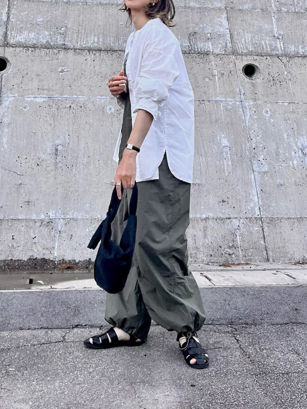 グリーン系のサロペット/オーバーオール、ブラック系のTシャツ/カットソー、ブラック系のハンドバッグを着用したレディースの春コーディネートの2枚目の写真