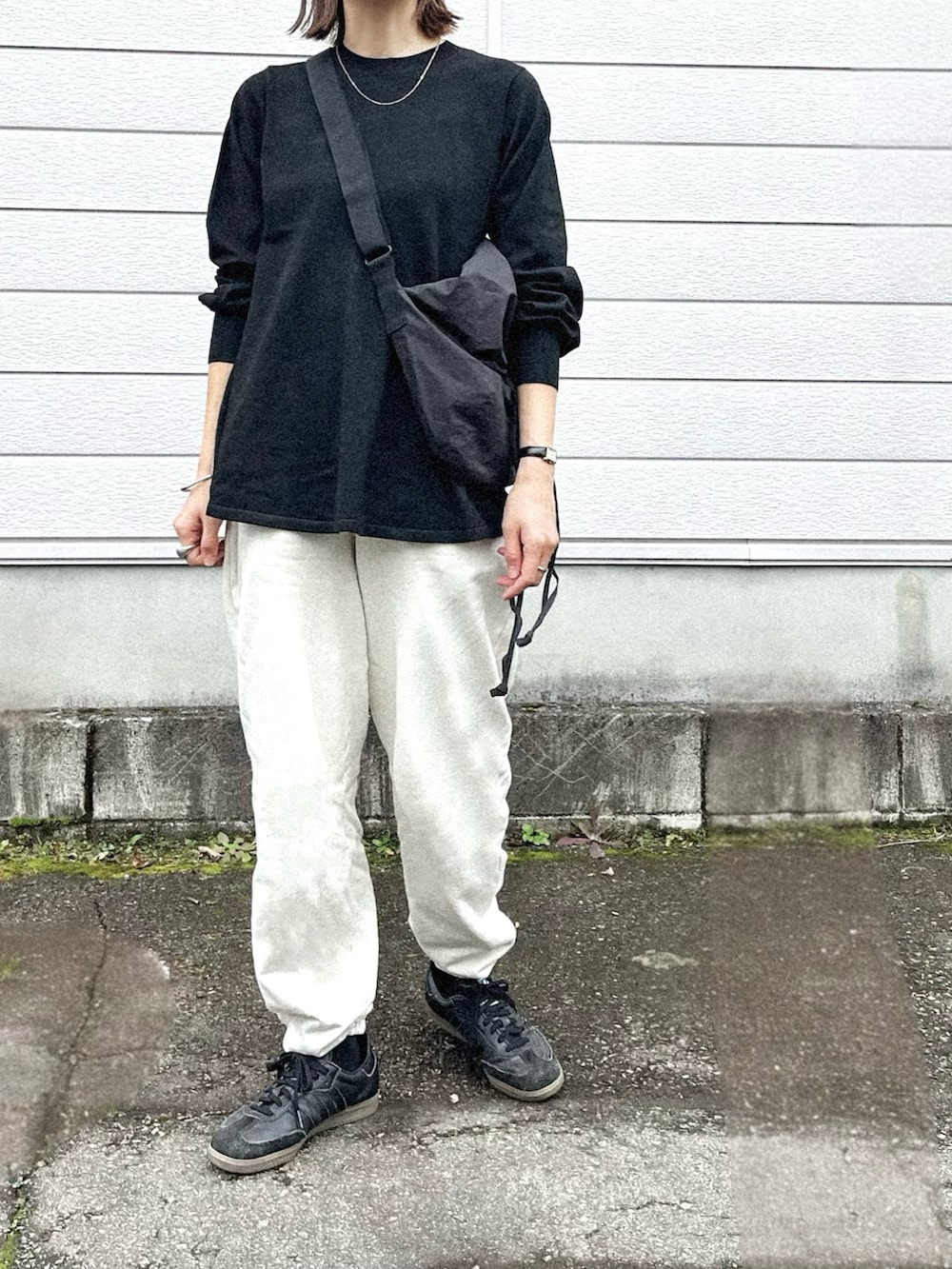 ブラック系のニット/セーター、ホワイト系のスウェットパンツ、ブラック系のスニーカーを着用したレディースの秋コーディネートの2枚目の写真