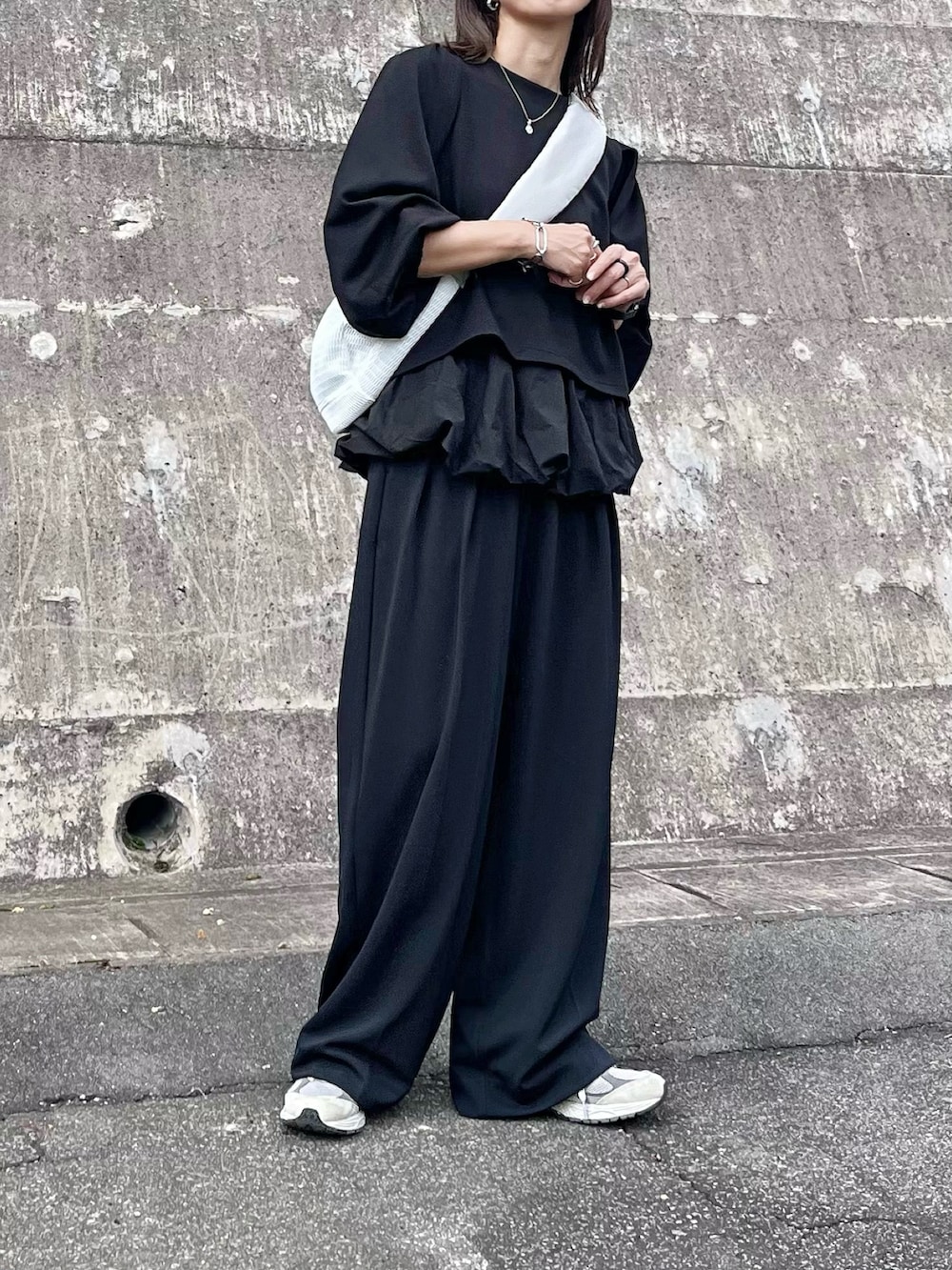 ブラック系のアンサンブル、ホワイト系のボディバッグ/ウエストポーチ、ピンク系の口紅/リップティント/グロスを着用したレディースの秋コーディネートの2枚目の写真