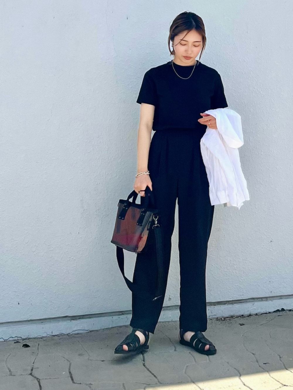 ブラウン系のショルダーバッグ、ブラック系のその他パンツ、ブラック系のTシャツ/カットソーを着用したレディースの春コーディネートの2枚目の写真