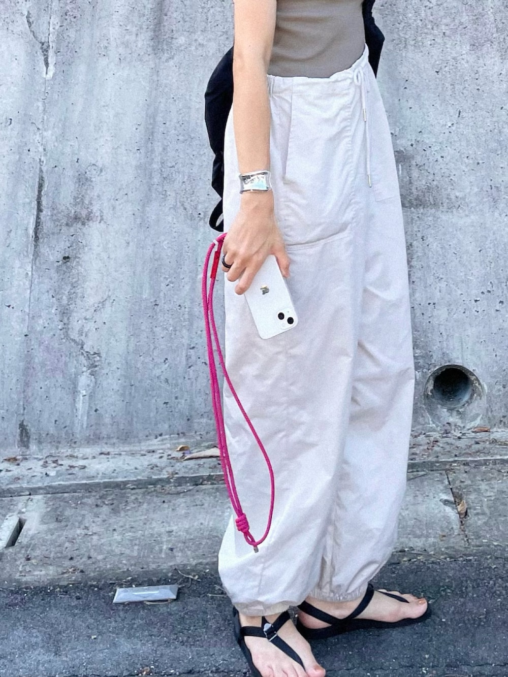 グリーン系のタンクトップ、ホワイト系のカーゴパンツ、ブラック系のサンダルを着用したレディースの夏コーディネートの3枚目の写真