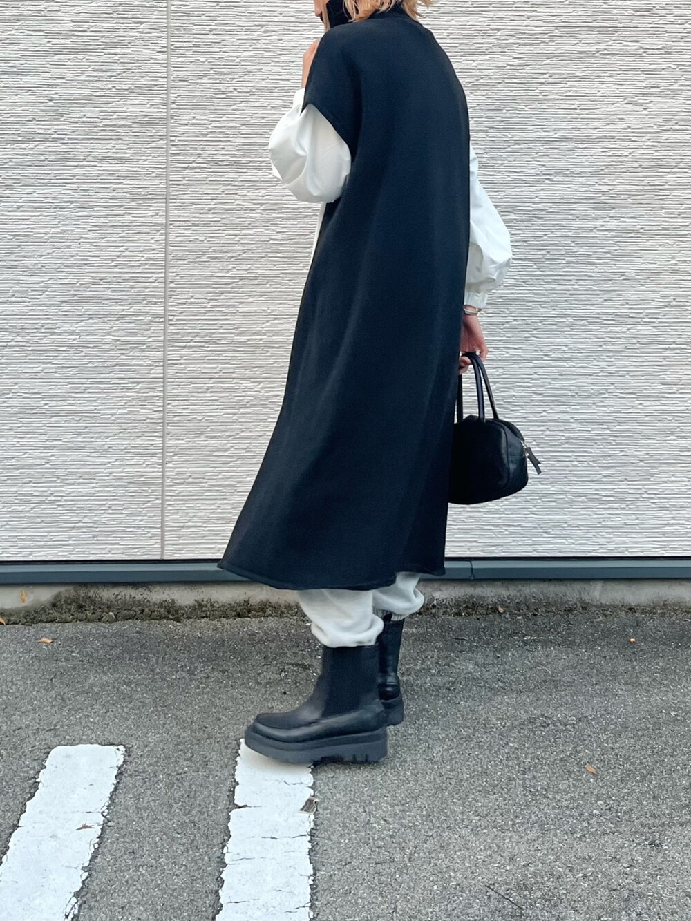 ブラック系のブーツ、ホワイト系のシャツ/ブラウス、ブラック系のニット/セーターを着用したレディースの秋コーディネートの2枚目の写真