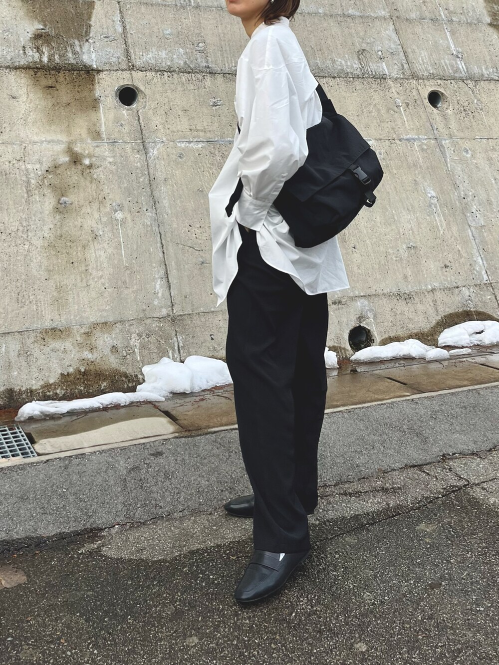 ブラック系のショルダーバッグ、ホワイト系のワンピース、ブラック系のレインシューズを着用したレディースの冬コーディネートの2枚目の写真
