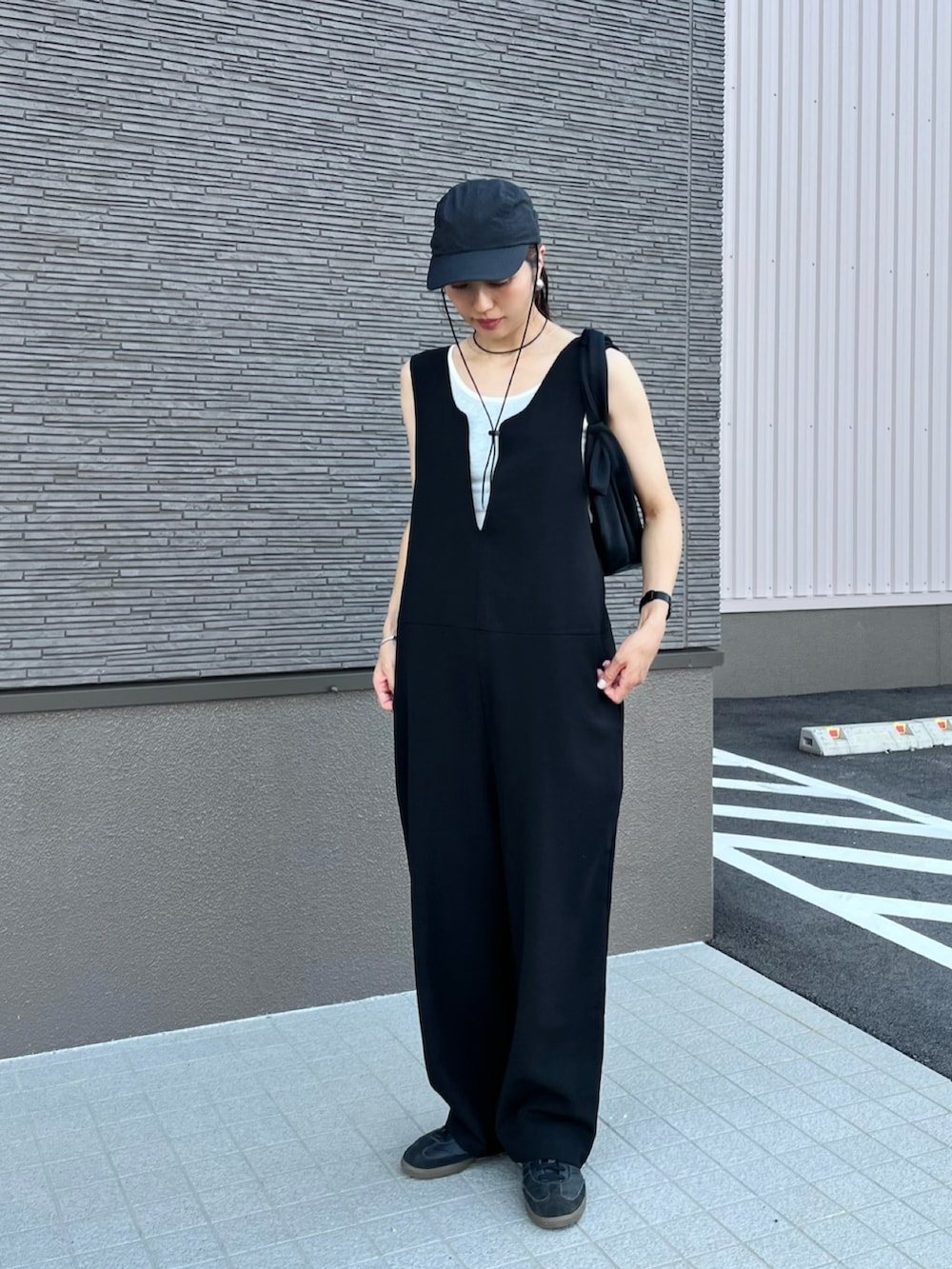 ブラック系のサロペット/オーバーオール、ブラック系のスニーカー、ホワイト系のタンクトップを着用したレディースの夏コーディネートの3枚目の写真