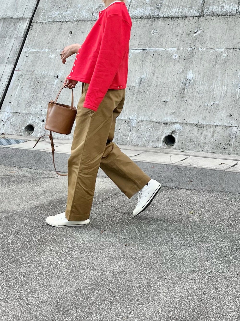 レッド系のカーディガン/ボレロ、イエロー系のハンドバッグ、ホワイト系のスニーカーを着用したレディースの秋コーディネートの3枚目の写真