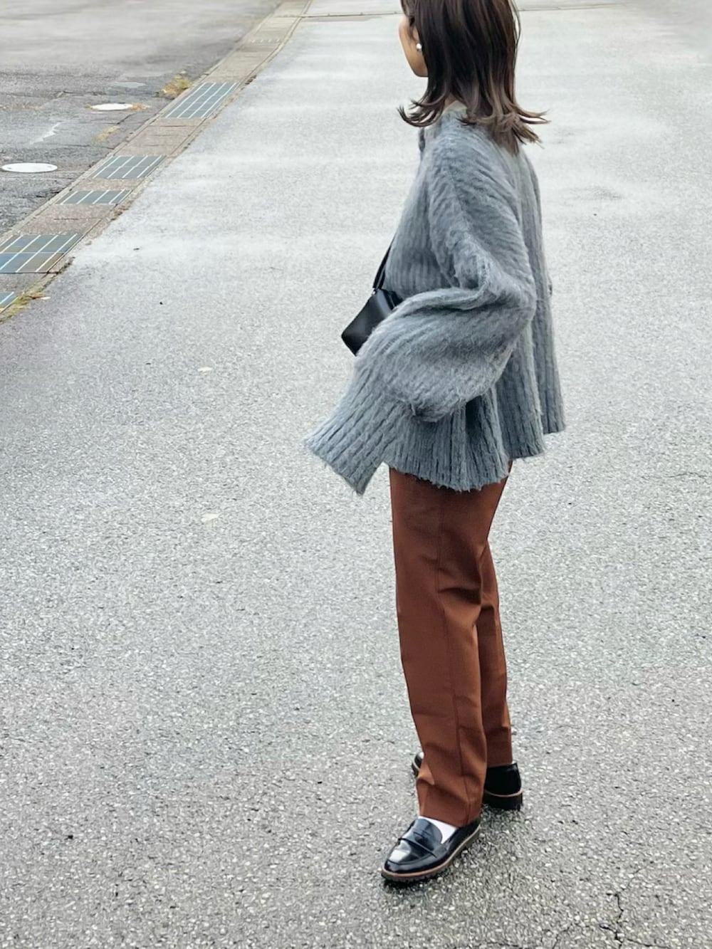 グレー系のカーディガン/ボレロ、ブラック系のローファー、ブラック系のショルダーバッグを着用したレディースの秋コーディネートの2枚目の写真