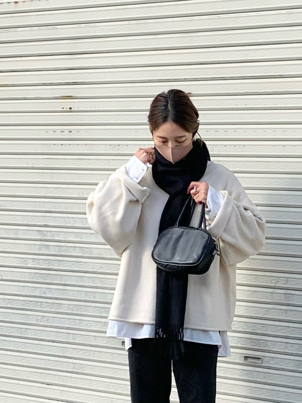 ホワイト系のニット/セーター、ホワイト系のシャツ/ブラウス、ブラック系のデニムパンツを着用したレディースの冬コーディネートの2枚目の写真