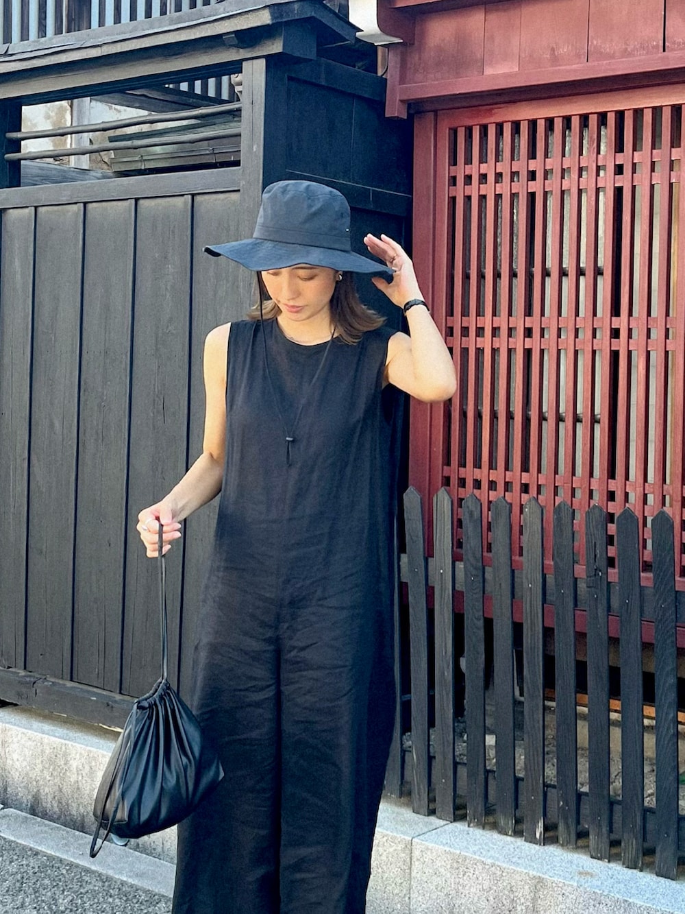 ブラック系のサロペット/オーバーオール、ブラック系のショルダーバッグ、ブラック系のサンダルを着用したレディースの秋コーディネートの2枚目の写真