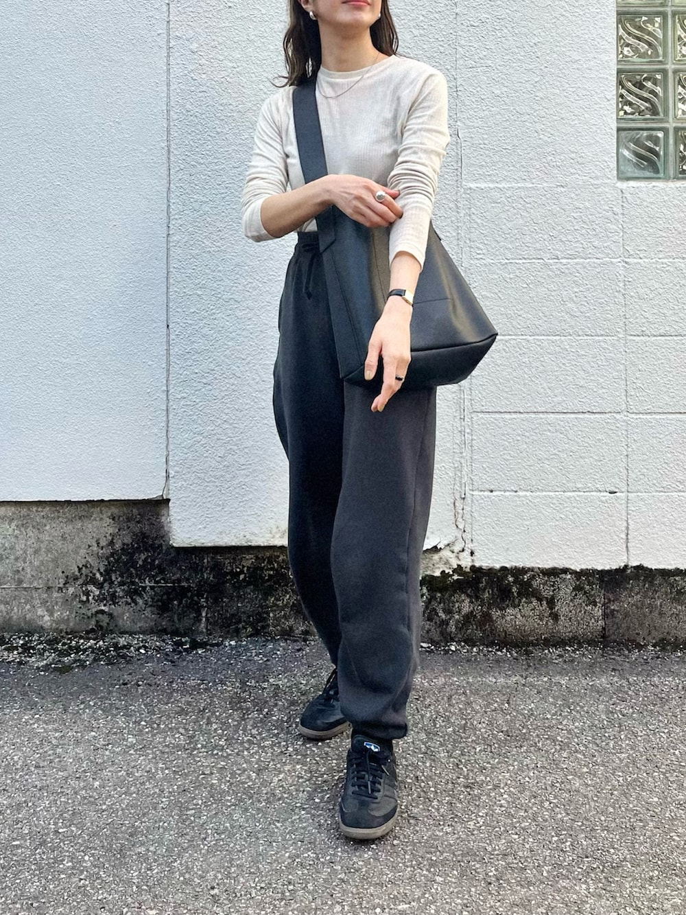 ホワイト系のTシャツ/カットソー、ブラック系のスラックス、ブラック系のショルダーバッグを着用したレディースの春コーディネートの2枚目の写真