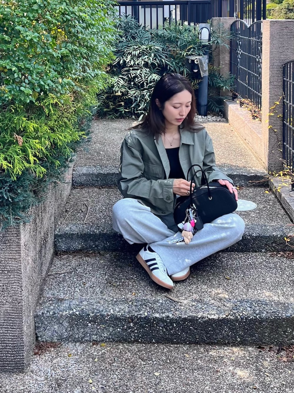 ブラック系のボストンバッグ、ブラック系のキャミソール、グリーン系のミリタリージャケットを着用したレディースの春コーディネートの4枚目の写真