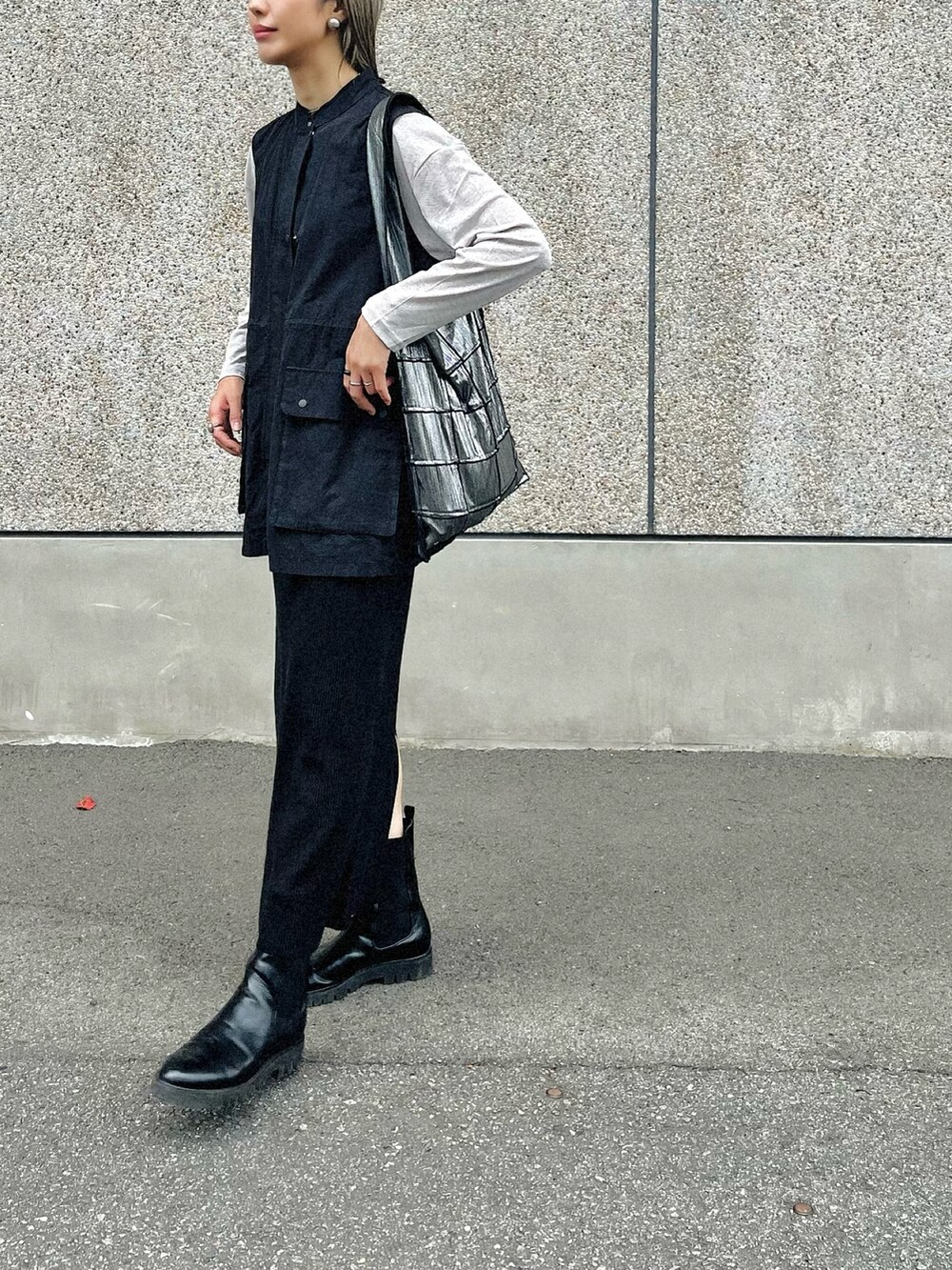 シルバー系のトートバッグ、ブラック系のスカート、ブラック系のブーツを着用したレディースの秋コーディネートの2枚目の写真