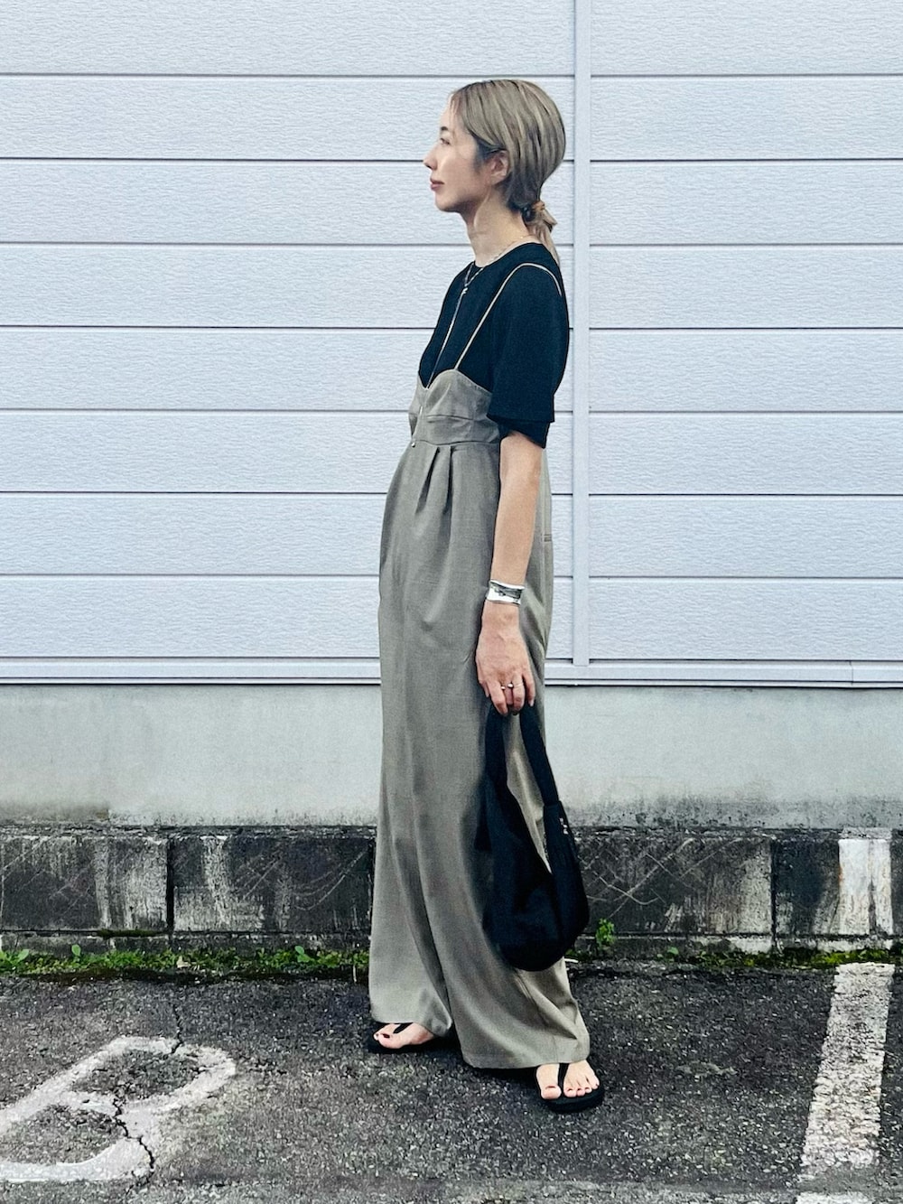 ブラック系のニット/セーター、グレー系のサロペット/オーバーオール、ブラック系のサンダルを着用したレディースの夏コーディネートの2枚目の写真