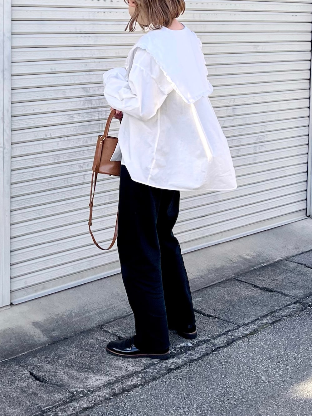 イエロー系のハンドバッグ、ブラック系のローファー、ブラック系のデニムパンツを着用したレディースの春コーディネートの2枚目の写真