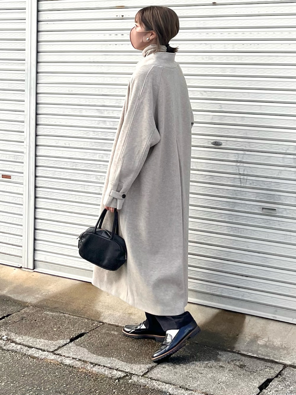 ベージュ系のチェスターコート、オレンジ系のマフラーを着用したレディースの冬コーディネートの3枚目の写真